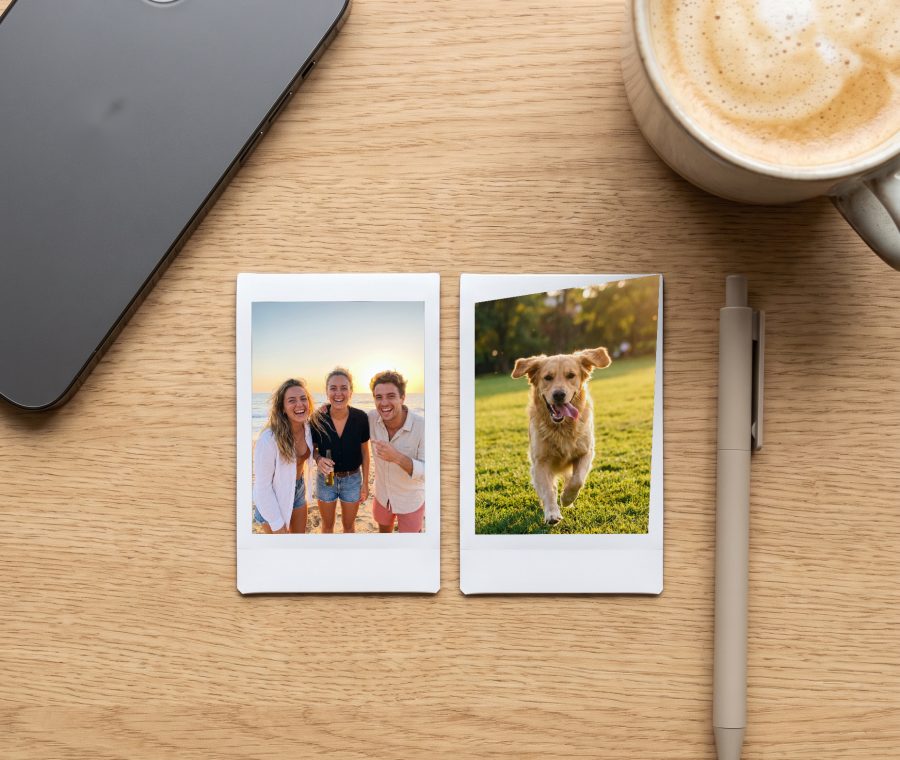 Two Instax Mini prints on a desk next to a phone, each the size of a credit card